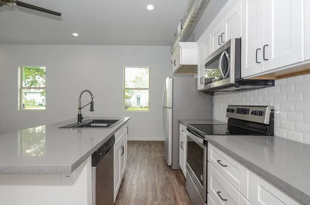 a kitchen with stainless steel appliances granite countertop a sink a stove and a refrigerator