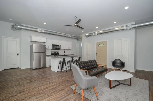 a kitchen with stainless steel appliances kitchen island granite countertop a refrigerator and a view of living room