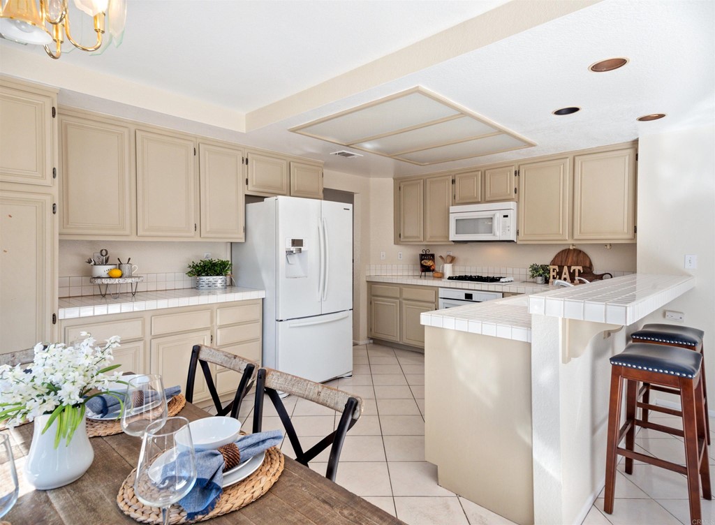 1593 Dawson Drive Vista, CA 92081 - Photo 17 of 40 a kitchen with refrigerator a stove a sink a dining table and chairs