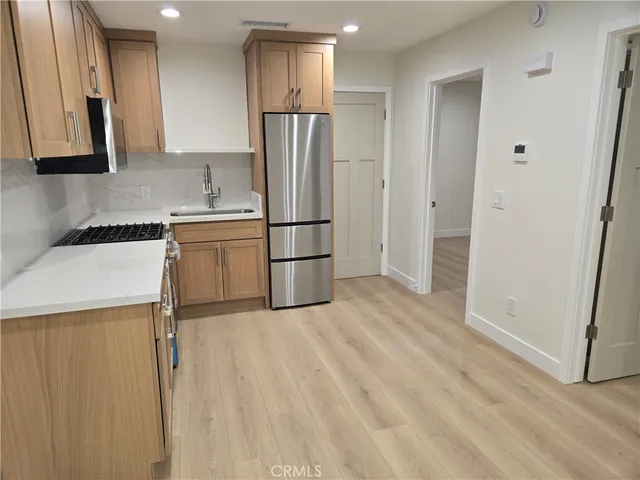 a kitchen with granite countertop a refrigerator a sink and white cabinets