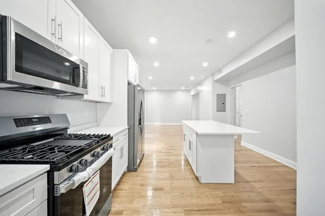 a kitchen with stainless steel appliances a stove a microwave and white cabinets