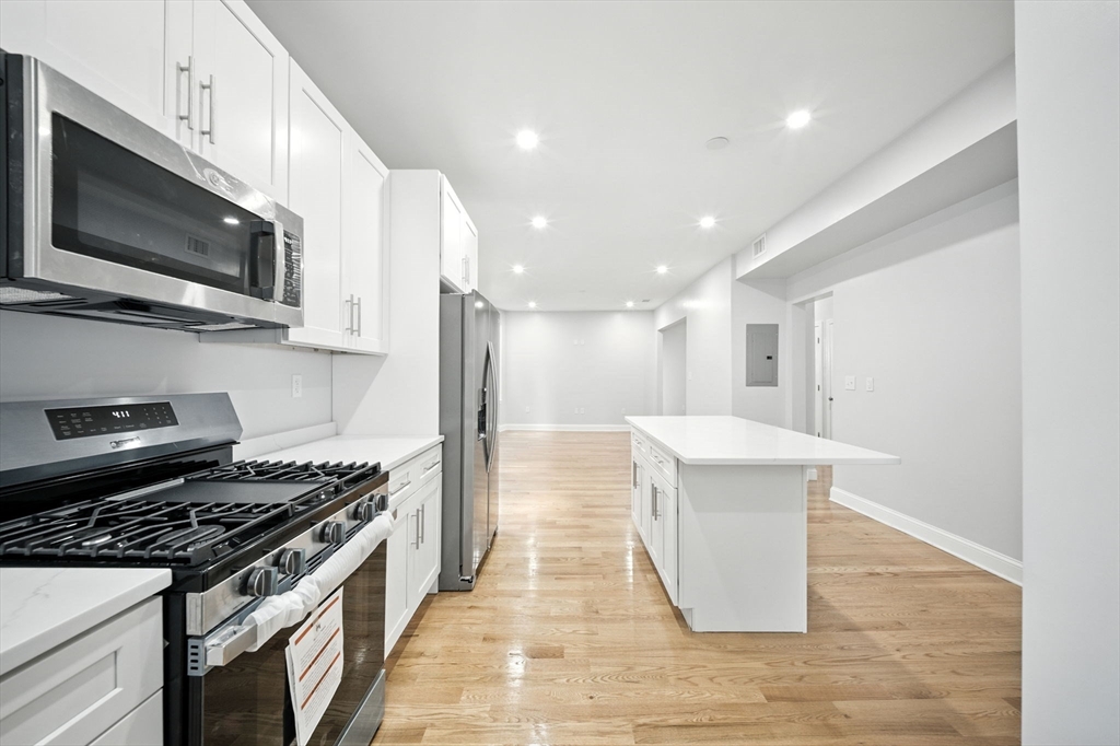 a kitchen with stainless steel appliances a stove a microwave and white cabinets