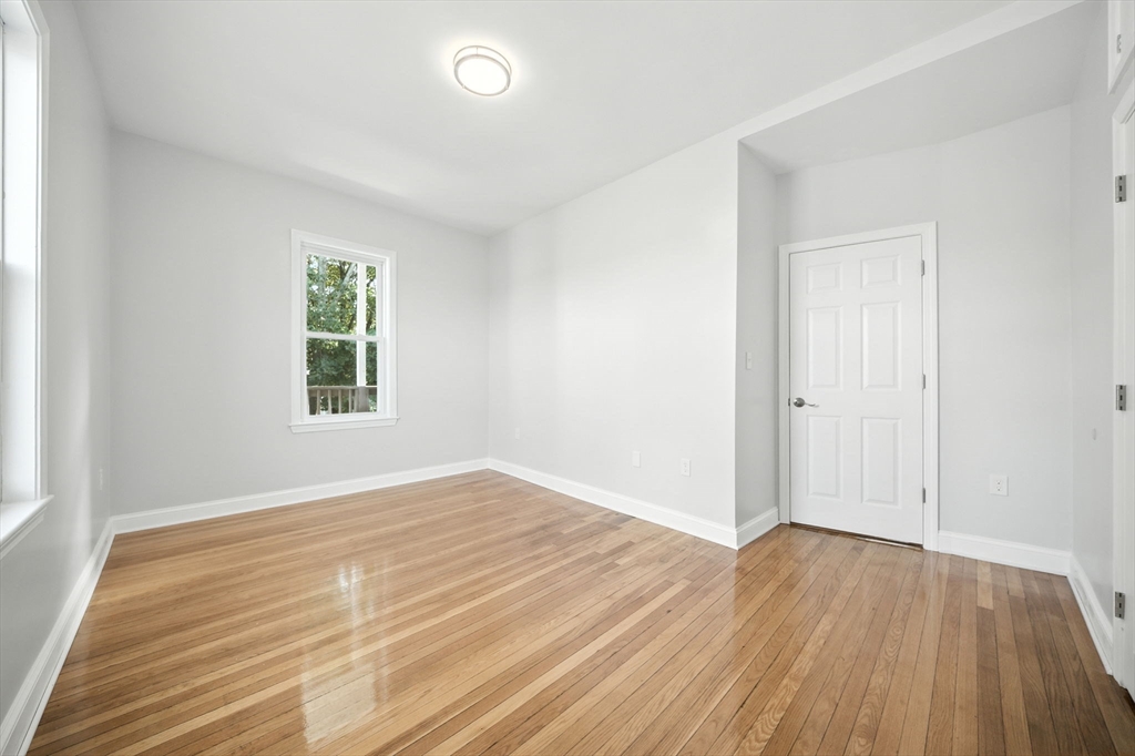 155 Wellington Hill Street, Unit 3 Boston, MA 02126 - Photo 13 of 20 an empty room with wooden floor and windows
