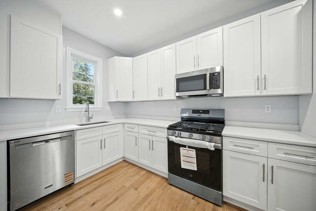 155 Wellington Hill Street, Unit 3 Boston, MA 02126 - Photo 2 of 20 a kitchen with white cabinets and appliances