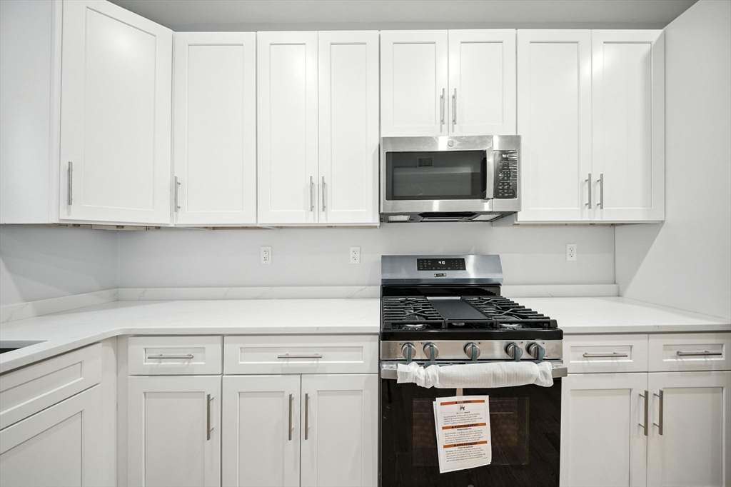 155 Wellington Hill Street, Unit 3 Boston, MA 02126 - Photo 3 of 20 a kitchen with granite countertop white cabinets and a stove a oven with white countertops