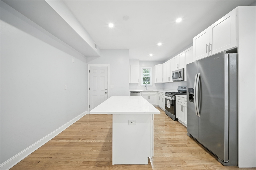 155 Wellington Hill Street, Unit 3 Boston, MA 02126 - Photo 4 of 20 a kitchen with stainless steel appliances a refrigerator and a stove top oven
