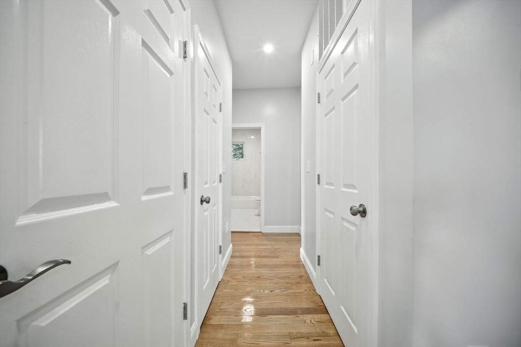 155 Wellington Hill Street, Unit 3 Boston, MA 02126 - Photo 9 of 20 a view of a hallway with wooden floor and a bathroom