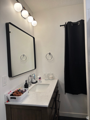 545 23rd Street Ogden, UT 84401 - Photo 25 of 28 Bathroom vanity featuring a light-toned countertop with integrated sink, dark wood-finish cabinetry, and matte black hardware