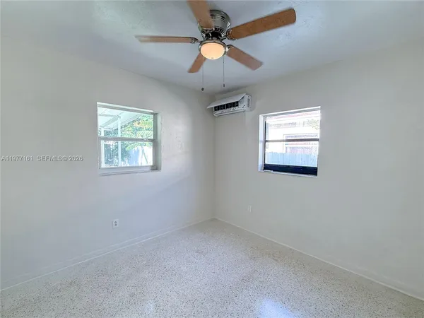an empty room with a window and a fan
