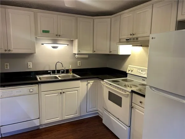 a kitchen with granite countertop white cabinets and white appliances