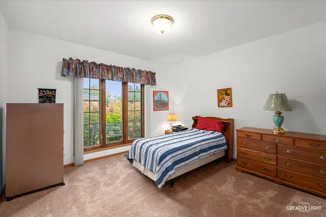 a bedroom with a bed and a dresser next to a window