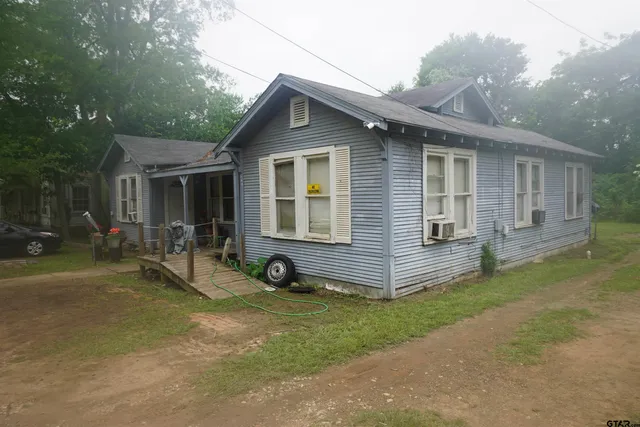 a view of a house with a yard and lawn chairs with a fire pit