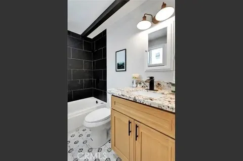 a bathroom with a granite countertop sink toilet and shower