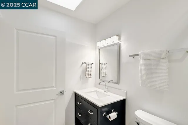 a bathroom with a toilet a sink a mirror and vanity