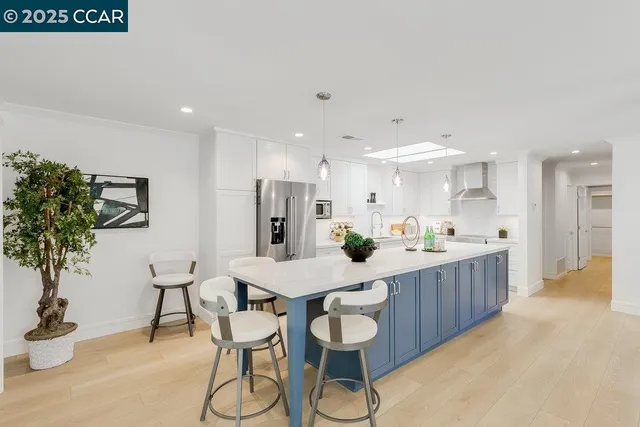 a kitchen with stainless steel appliances kitchen island granite countertop a table chairs in it and white cabinets