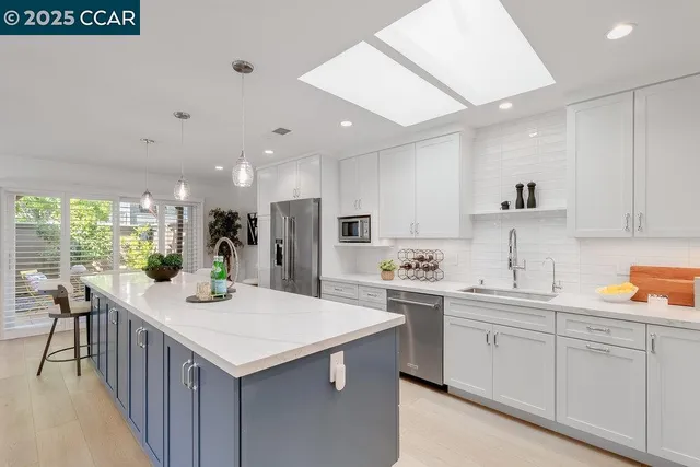 a kitchen with kitchen island a sink a stove a refrigerator and white cabinets with wooden floor