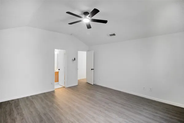 an empty room with wooden floor and ceiling fan