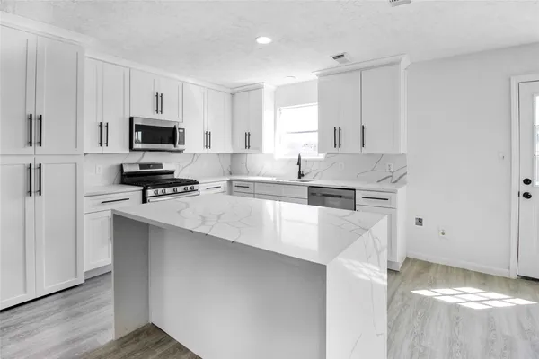 a kitchen with stainless steel appliances a stove a sink a microwave and cabinets