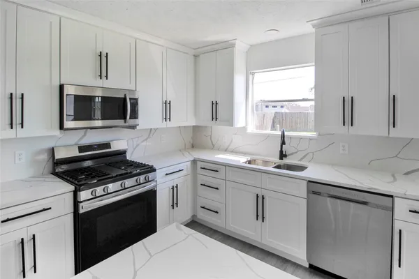 a kitchen with cabinets appliances a sink and a window