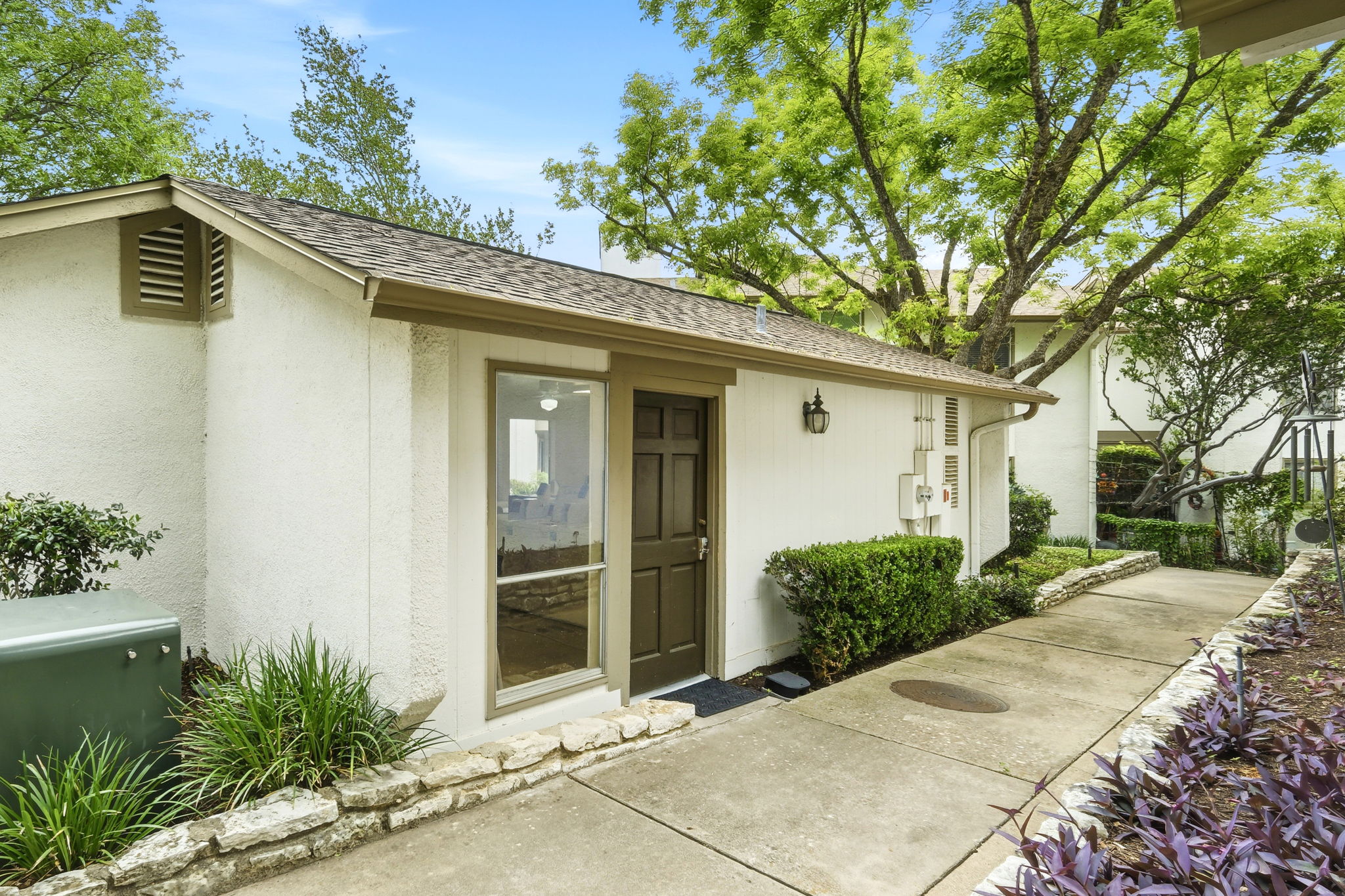 6910 Hart Lane, Unit 912 Austin, TX 78731 - Photo 27 of 36 Exterior entrance featuring a brown door, large window, and wall-mounted light fixture