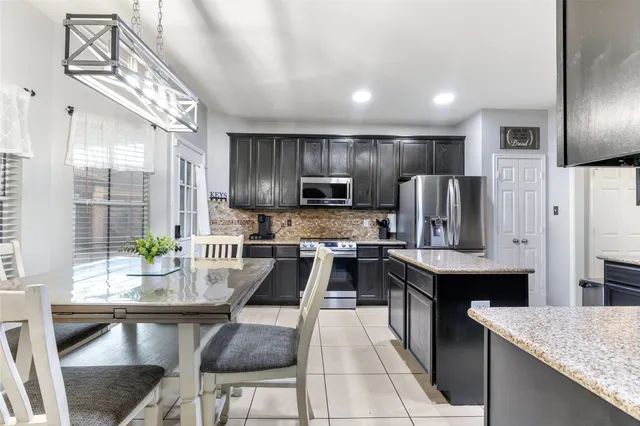a kitchen with stainless steel appliances kitchen island granite countertop a table chairs in it and wooden floors