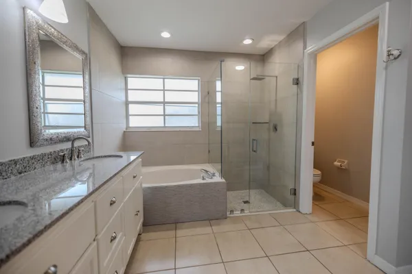 a spacious bathroom with a granite countertop sink a mirror and a bathtub