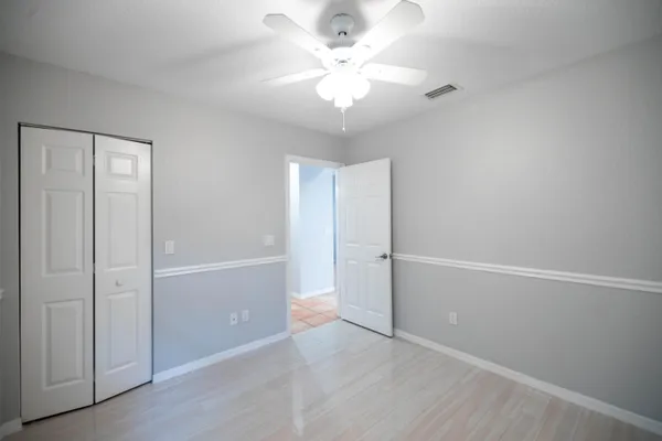 an empty room with closet and a ceiling fan