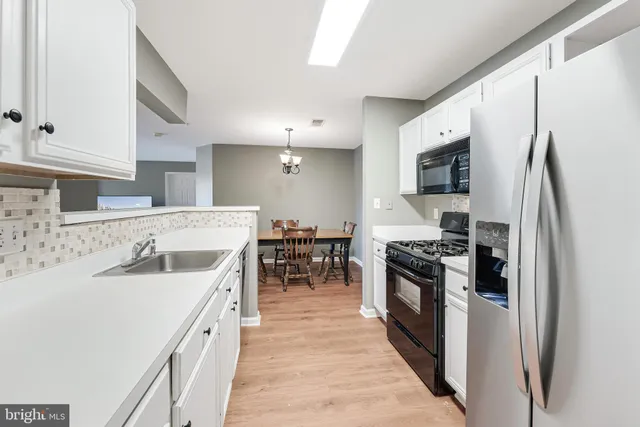 a kitchen with stainless steel appliances granite countertop a refrigerator a stove a sink a dining table and chairs