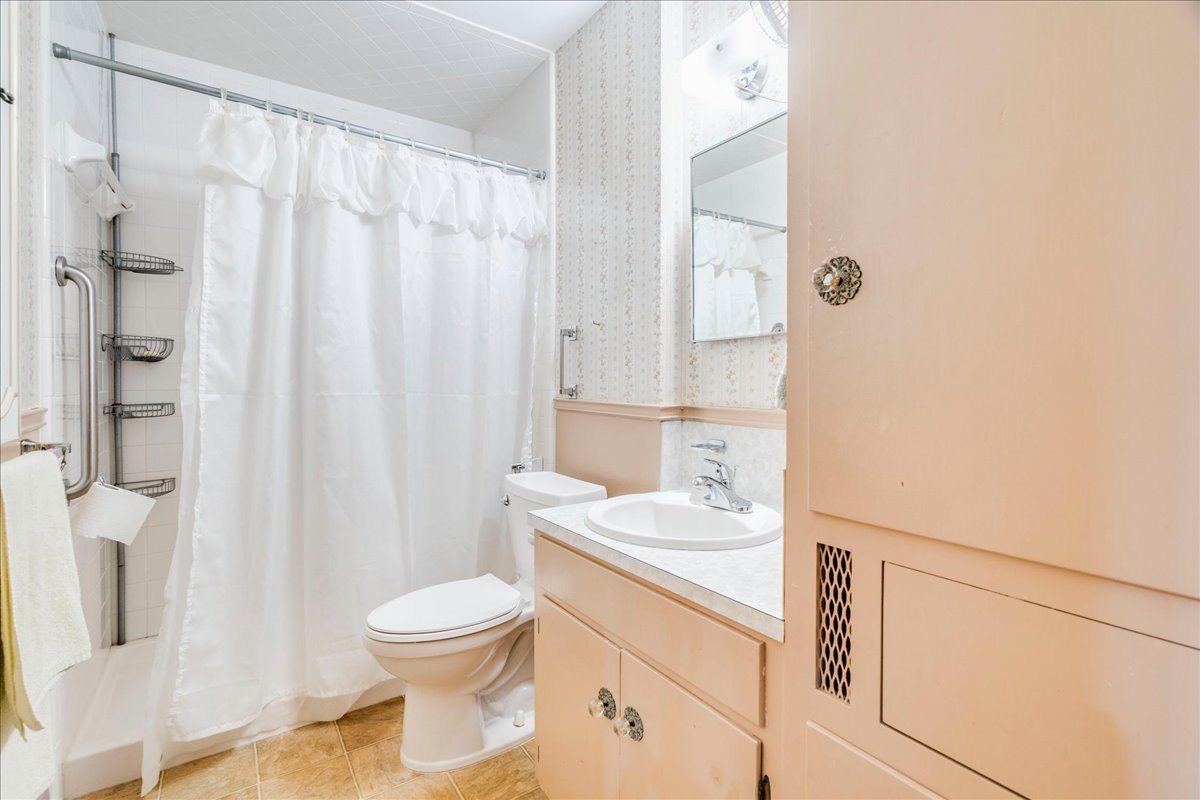 6626 Isabelle Drive Austin, TX 78752 - Photo 21 of 27 Bathroom featuring a shower stall with grab bar, built-in shelving, and a toilet