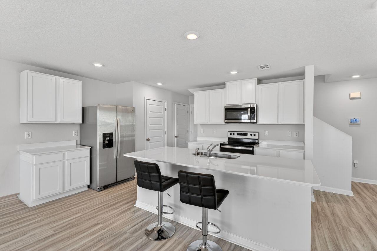 2637 Saltgrass Way Crestview, FL 32536 - Photo 12 of 47 a kitchen with stainless steel appliances kitchen island granite countertop a refrigerator and microwave