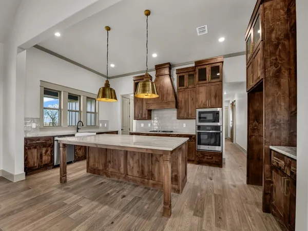 a kitchen with stainless steel appliances granite countertop a sink a stove and a wooden floors