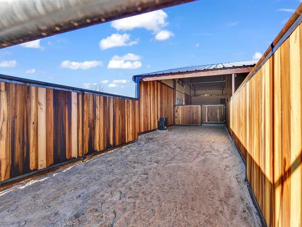 a view of a backyard with wooden fence and large windows