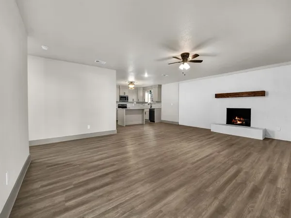 an empty room with a fireplace and a ceiling fan