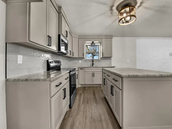 a kitchen with stainless steel appliances granite countertop a sink and a stove top oven
