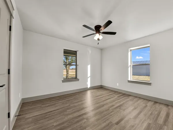 a view of an empty room with a window and wooden floor