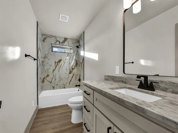 a bathroom with a granite countertop sink toilet and shower