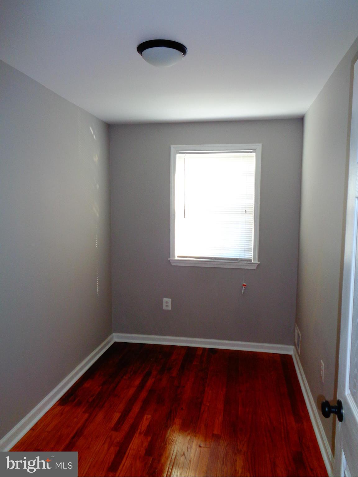 2109 Hawthorne Road Baltimore, MD 21220 - Photo 17 of 28 a view of an empty room with wooden floor and a window