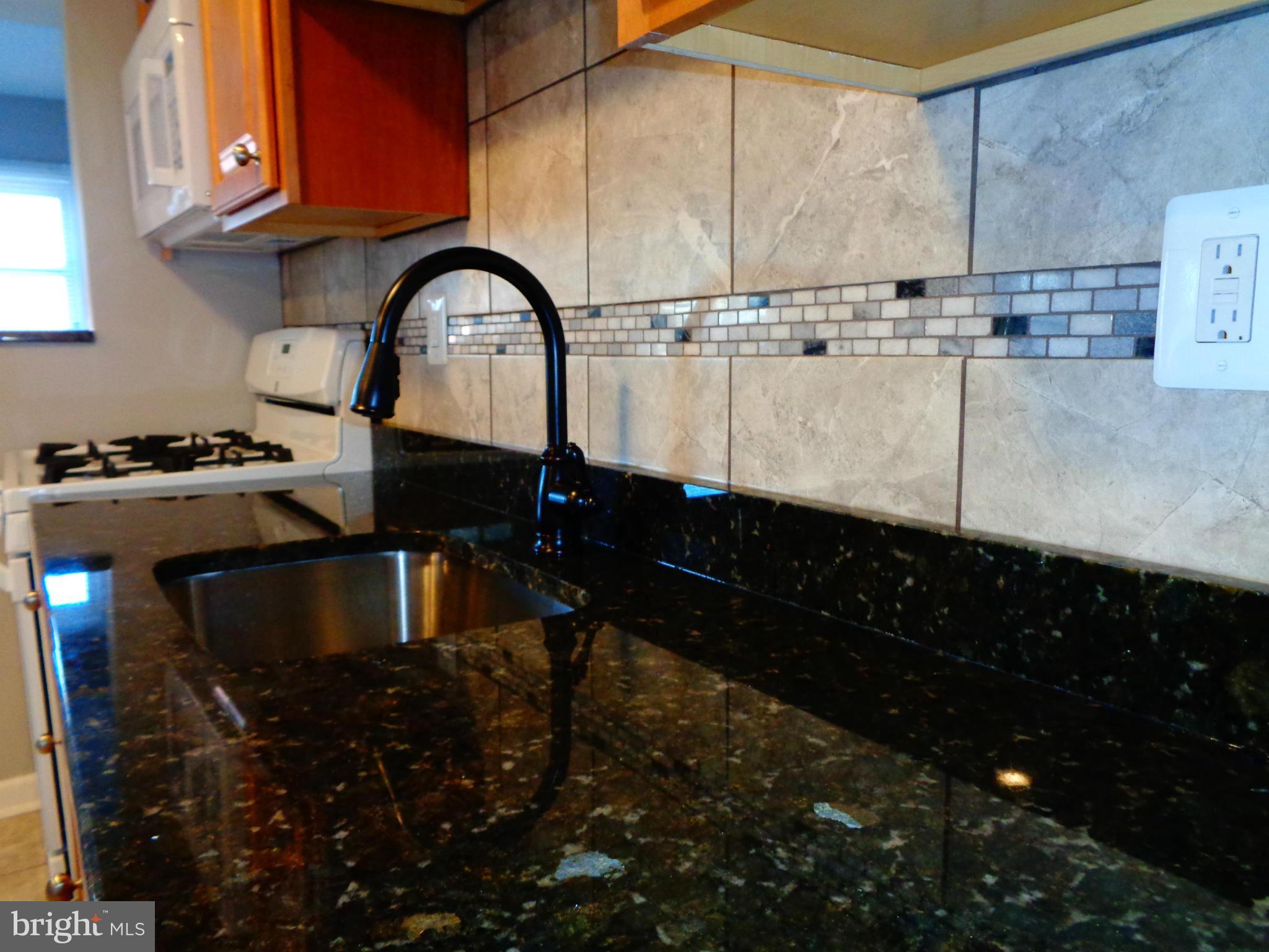 2109 Hawthorne Road Baltimore, MD 21220 - Photo 8 of 28 a kitchen with granite countertop a stove a sink and a microwave