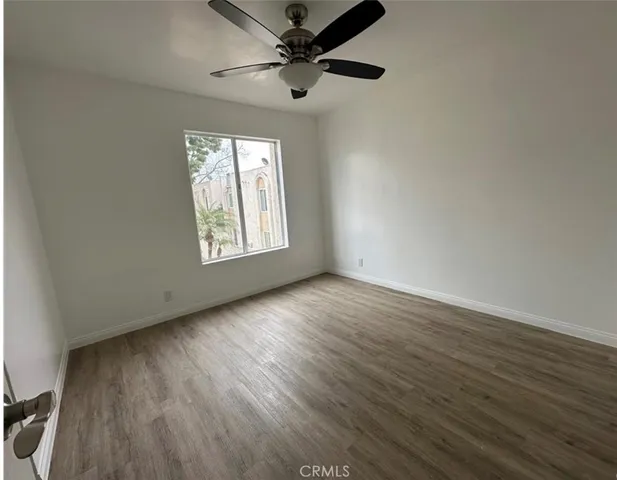 an empty room with wooden floor fan and windows