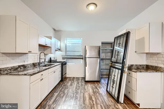 a kitchen with a refrigerator a stove top oven and white cabinets