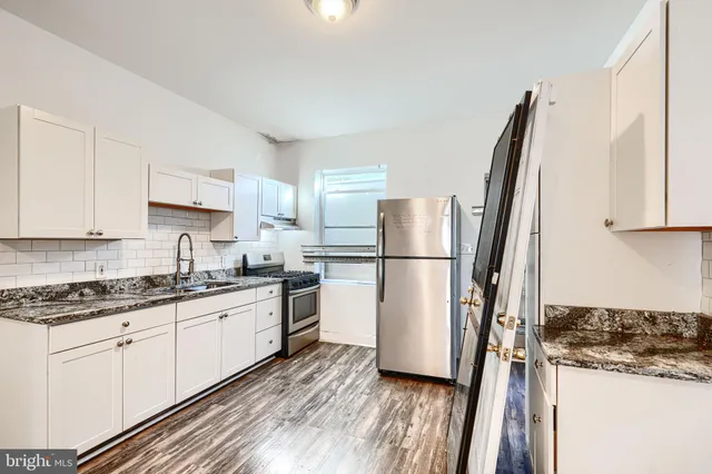 a kitchen with a refrigerator a sink and white cabinets