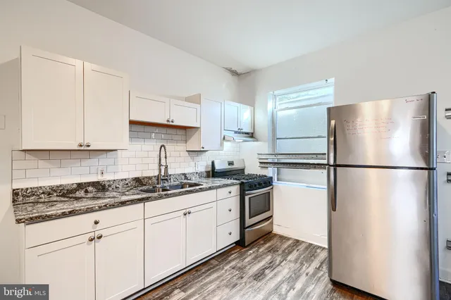 a kitchen with stainless steel appliances granite countertop a refrigerator a stove a sink and white cabinets