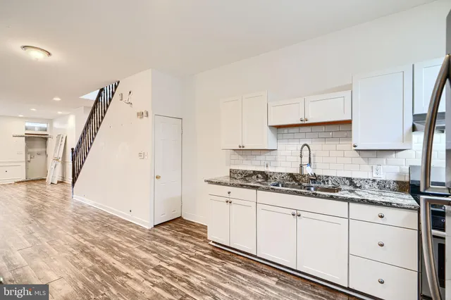 a kitchen with granite countertop a sink a refrigerator and cabinets
