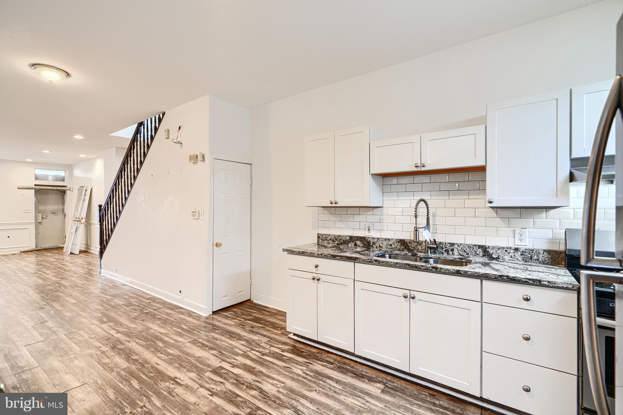 1601 East 28th Street Baltimore, MD 21218 - Photo 18 of 34 a kitchen with granite countertop a sink a refrigerator and cabinets