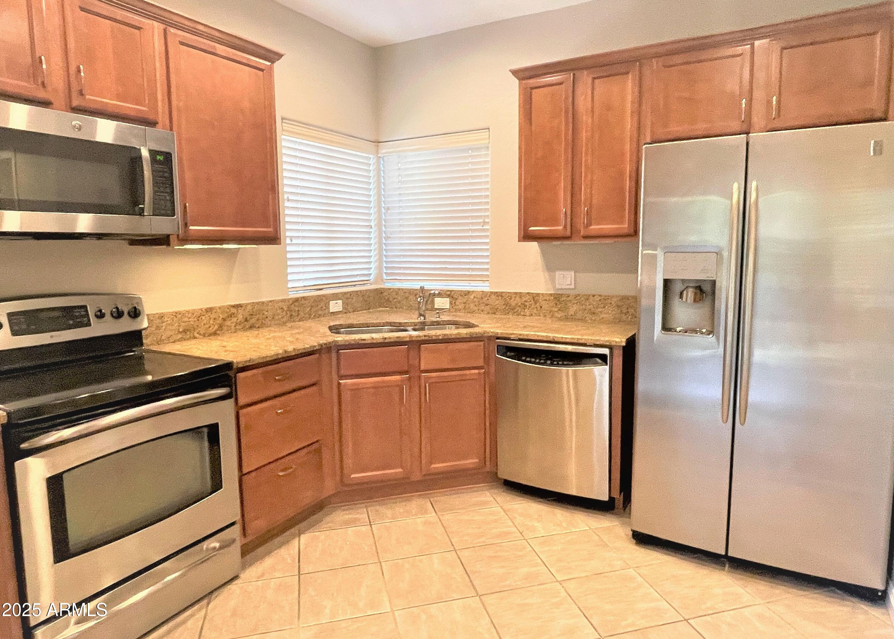 3935 East Rough Rider Road, Unit 1167 Phoenix, AZ 85050 - Photo 9 of 29 a kitchen with stainless steel appliances granite countertop a refrigerator sink and stove
