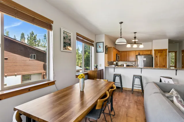 a view of a dining room and livingroom with furniture wooden floor a rug a painting and a chandelier