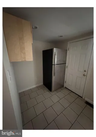 a view of a refrigerator in kitchen and an empty room