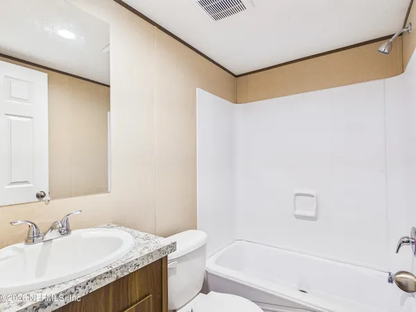 a bathroom with a granite countertop sink a toilet and shower