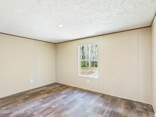 an empty room with wooden floor and window