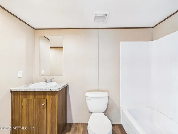 a bathroom with a granite countertop sink and a toilet